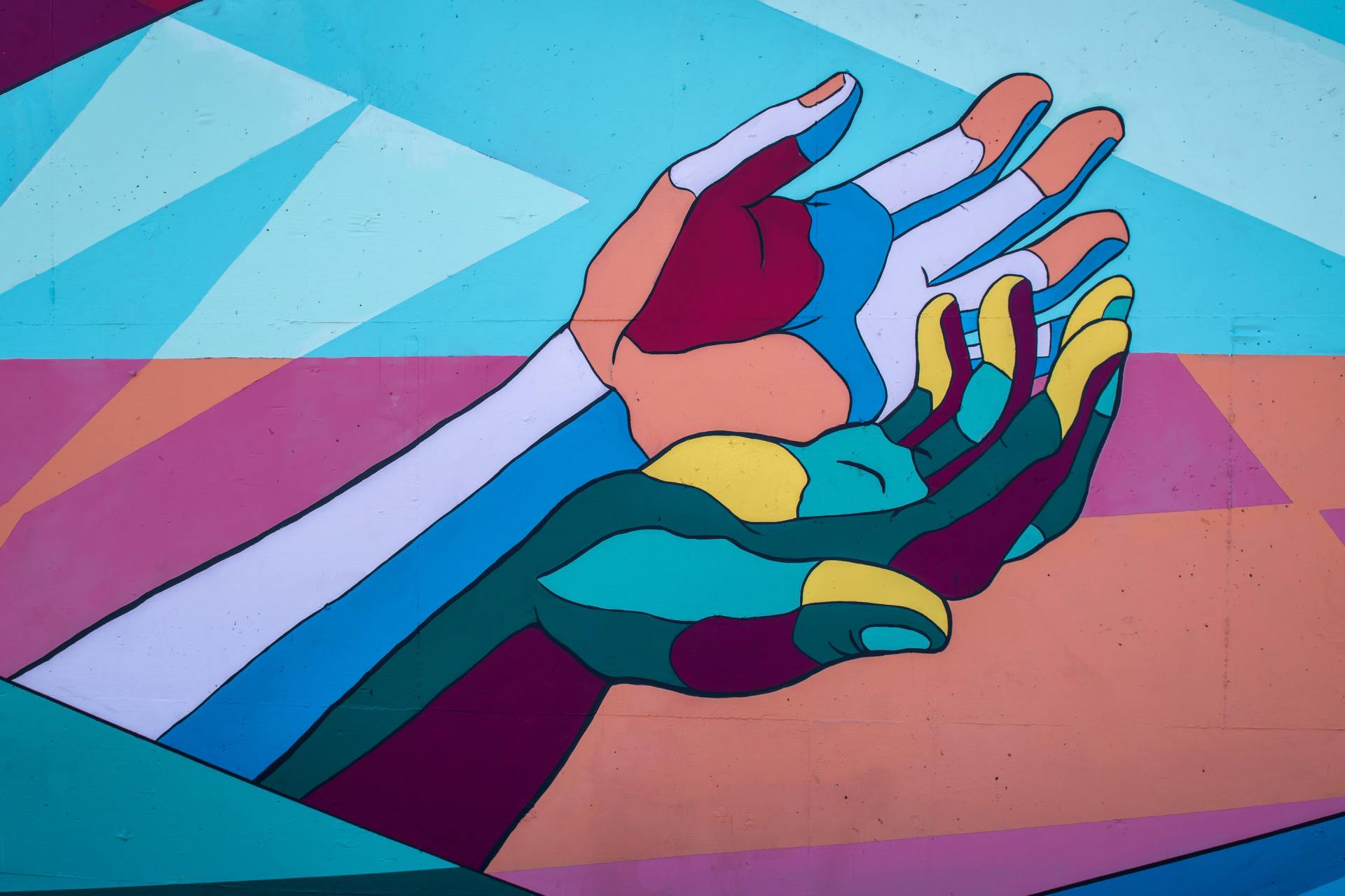 A colorful mural or artistic illustration showing multiple hands reaching toward each other in various shades of blue, purple, and yellow, symbolizing community support and connection