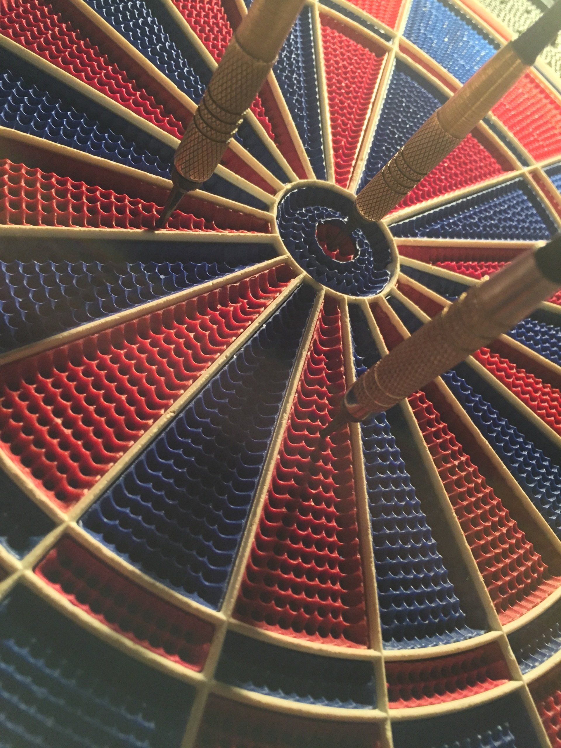 Dartboard with three darts, one of which has marked a bullseye.