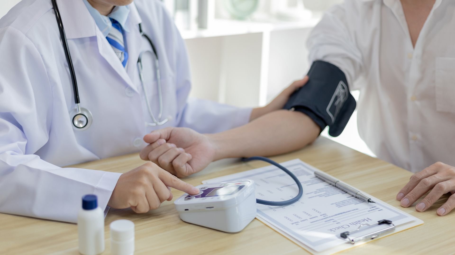 Doctor taking a patient's blood pressure with an automatic monitor in an office setting.