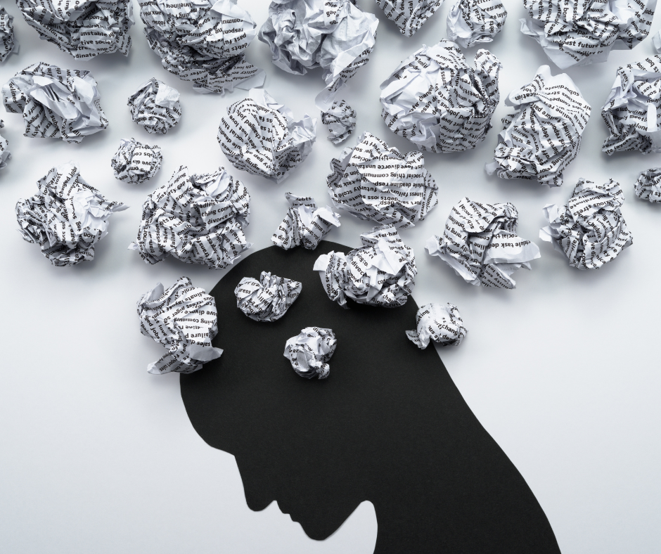 Silhouette head with crumpled paper balls above, representing stressful thoughts.