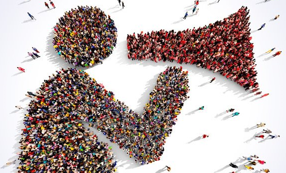 An aerial view of a large crowd of people arranged to form the shape of a person speaking into a megaphone