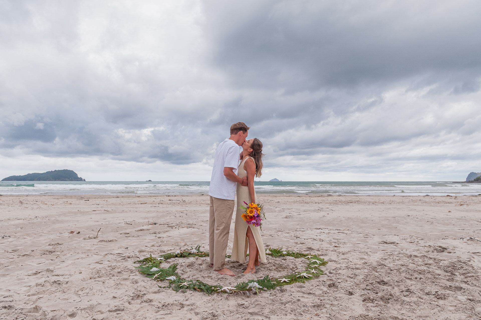 Ein intimer Moment voller Liebe und Emotionen. Brautpaar küsst sich nach ihrer freien Hochzeitszeremonie am Strand 