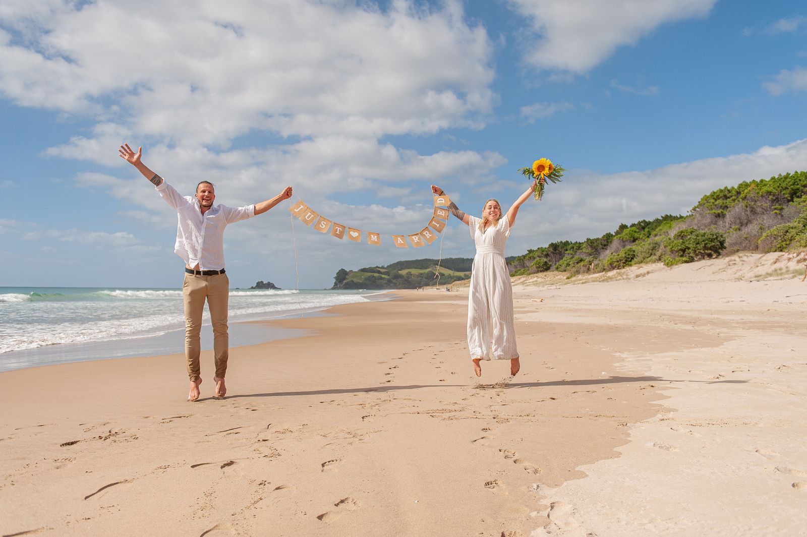 Pure Freude und entspannte Atmosphäre. Brautpaar ganz happy nach ihrer intimen Trauung am Strand von Opoutere in Neuseeland
