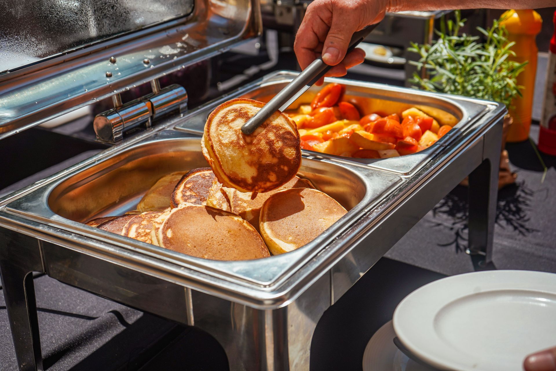 Buffet tray with food being served: pancakes, scrambled eggs, and roasted vegetables