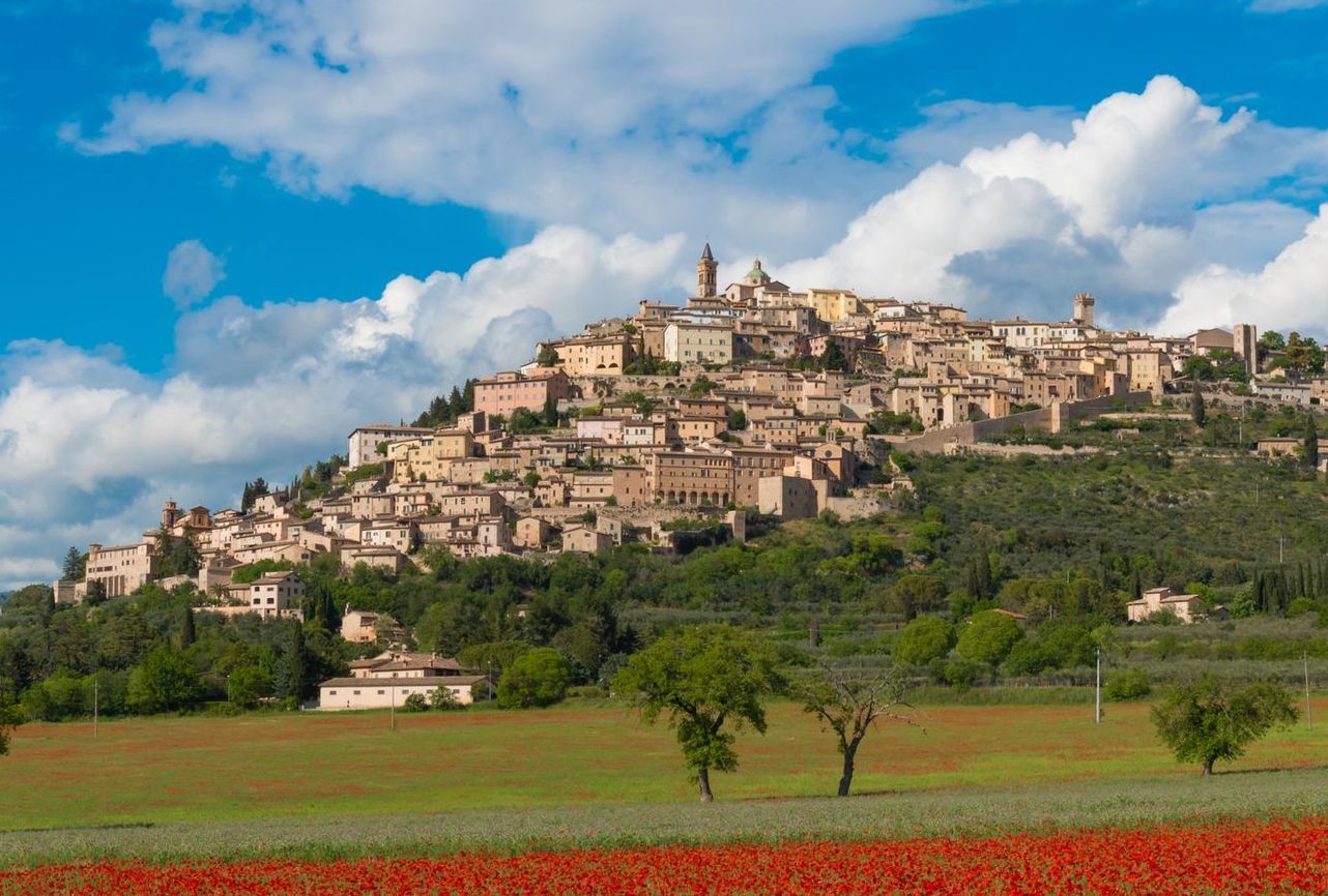 Villaggio collinare con edifici in pietra che si affacciano su campi verdi