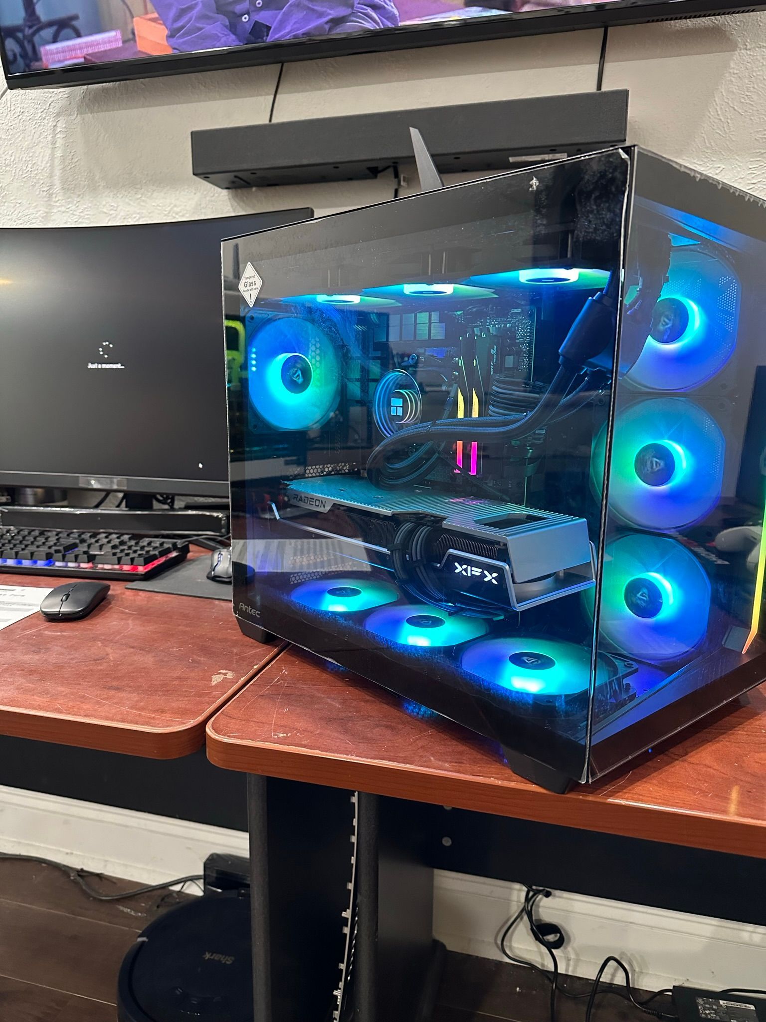 A computer is sitting on top of a wooden table next to a computer monitor.