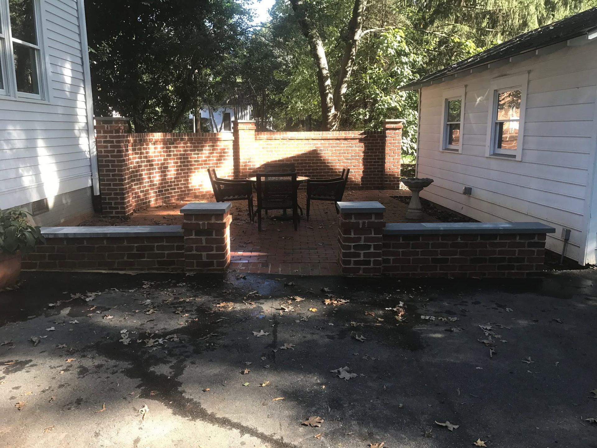 Brick patio with steps between two houses and a small table in the back
