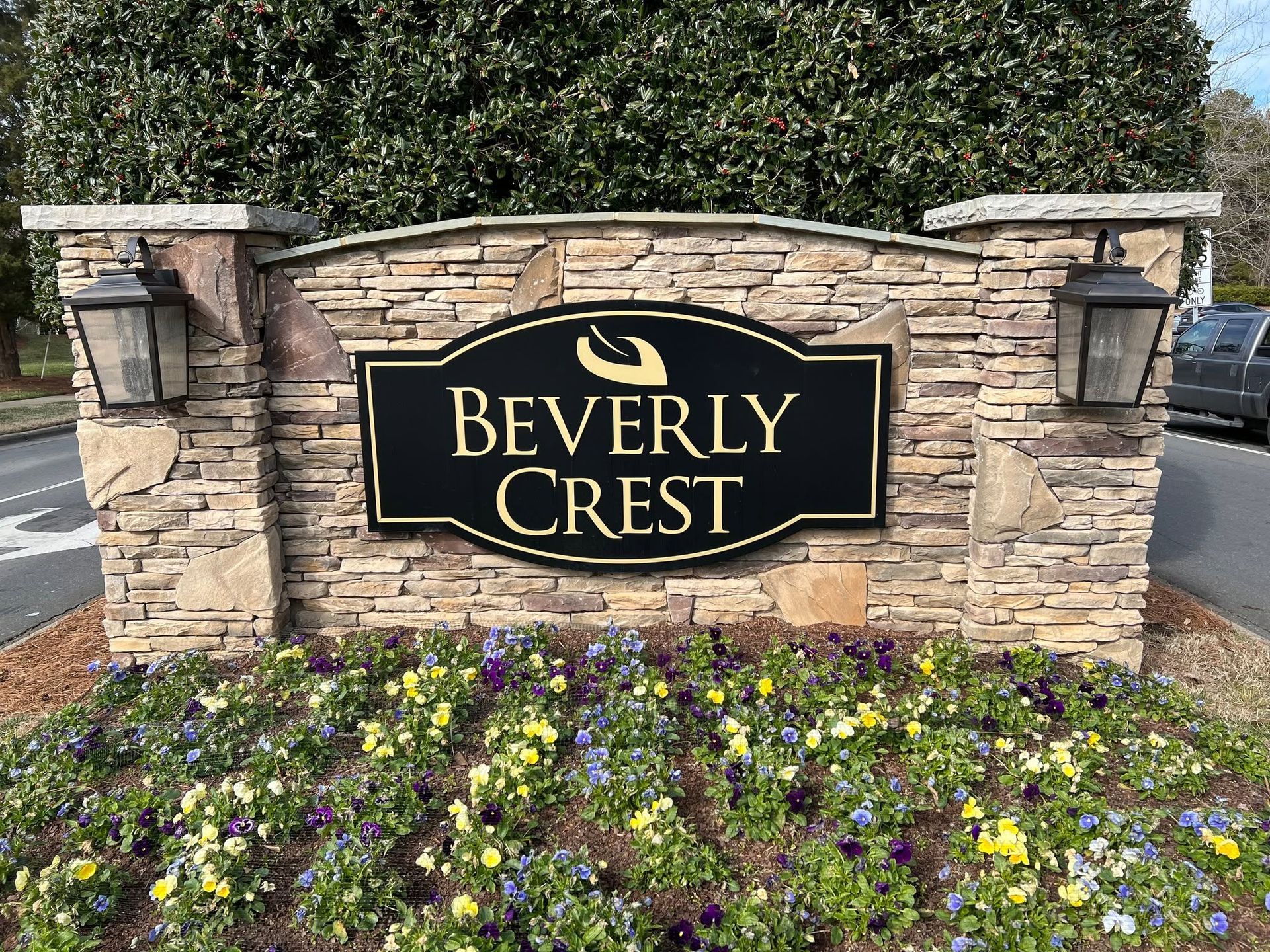 Beverly Crest community sign on a stone wall with flower bed and lanterns