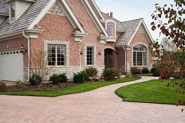 Brick suburban house with arched entry, manicured lawn, and curved driveway