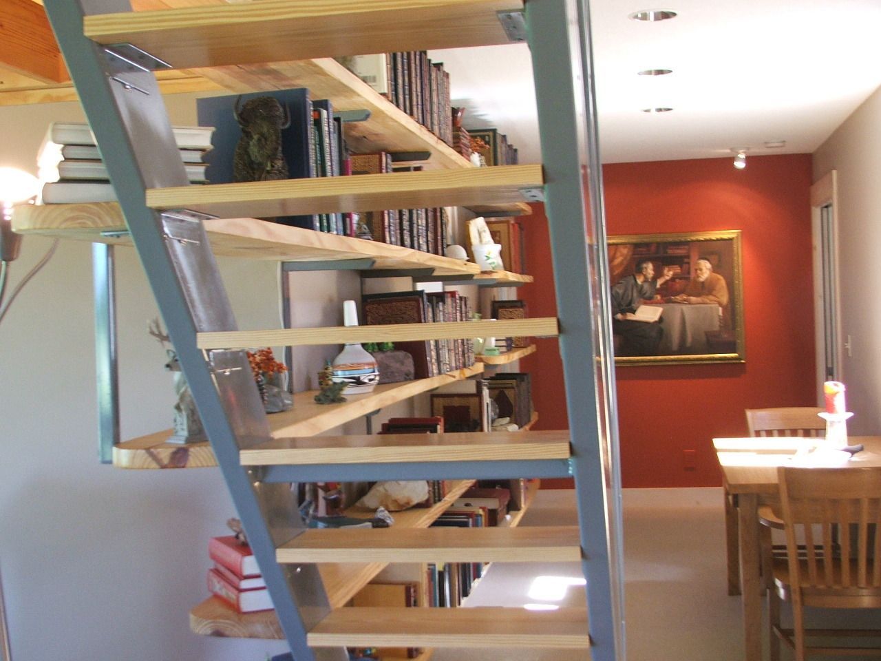 Modern loft interior with metal staircase, wooden shelves, and dining table in the background.