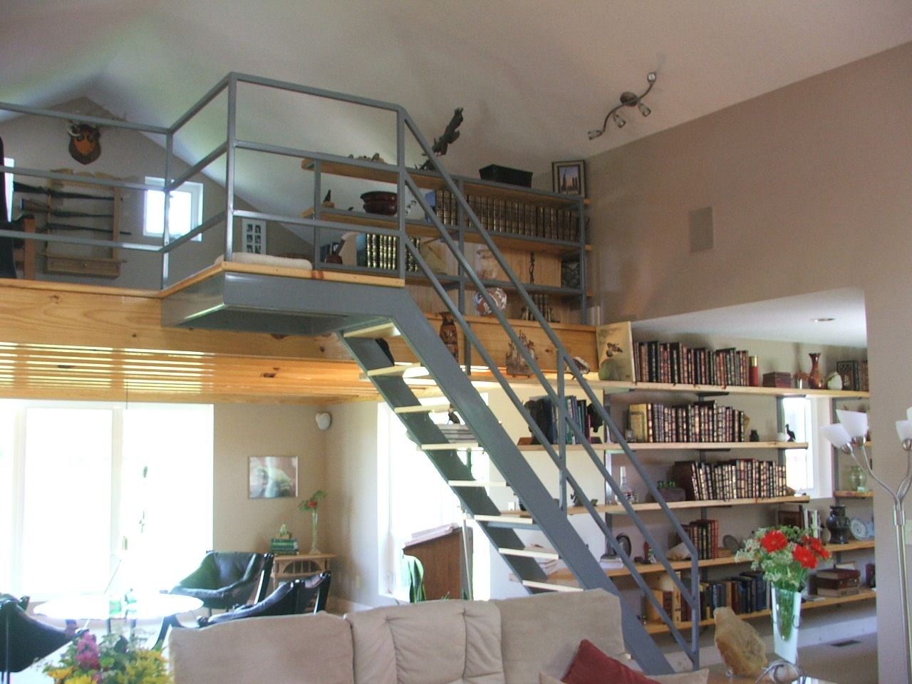 Loft interior with metal staircase, bookshelves, and bright windows