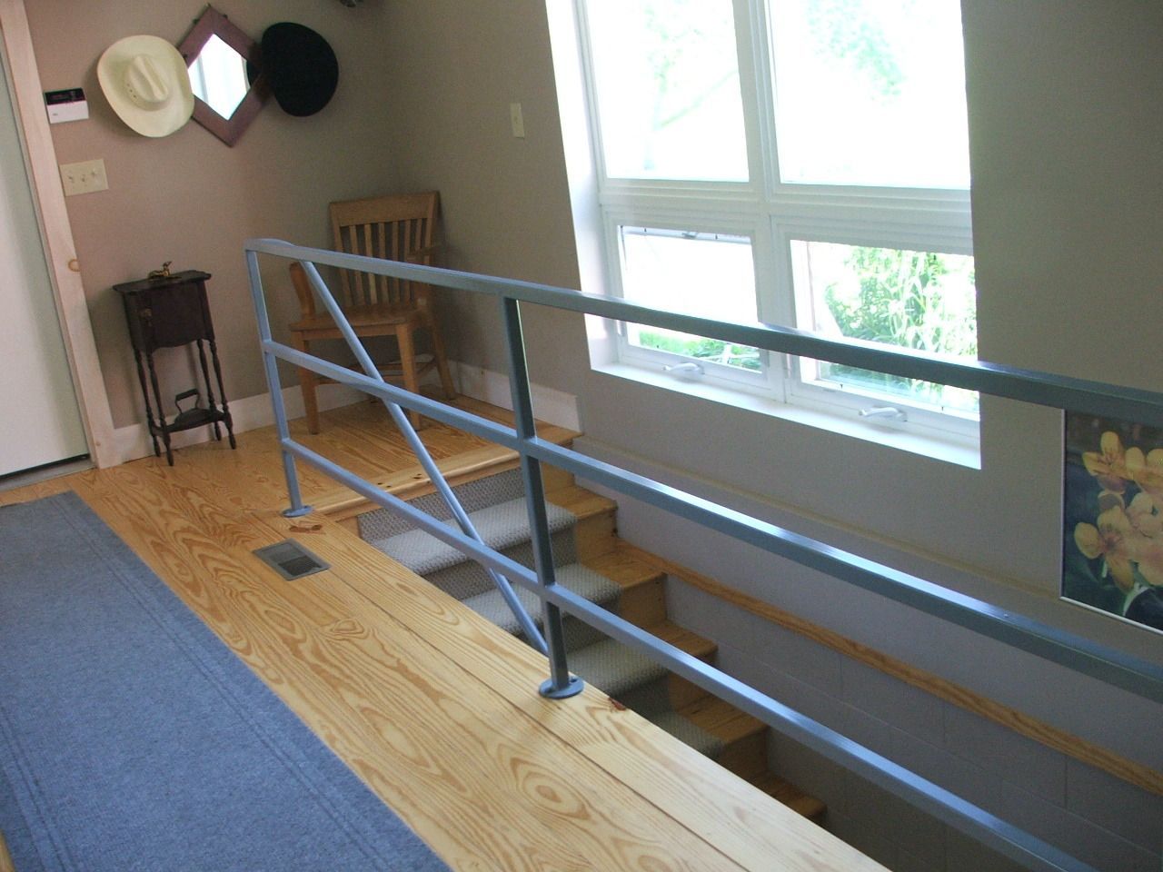 Indoor ramp with blue railings beside a bright window and wooden floor in a hallway