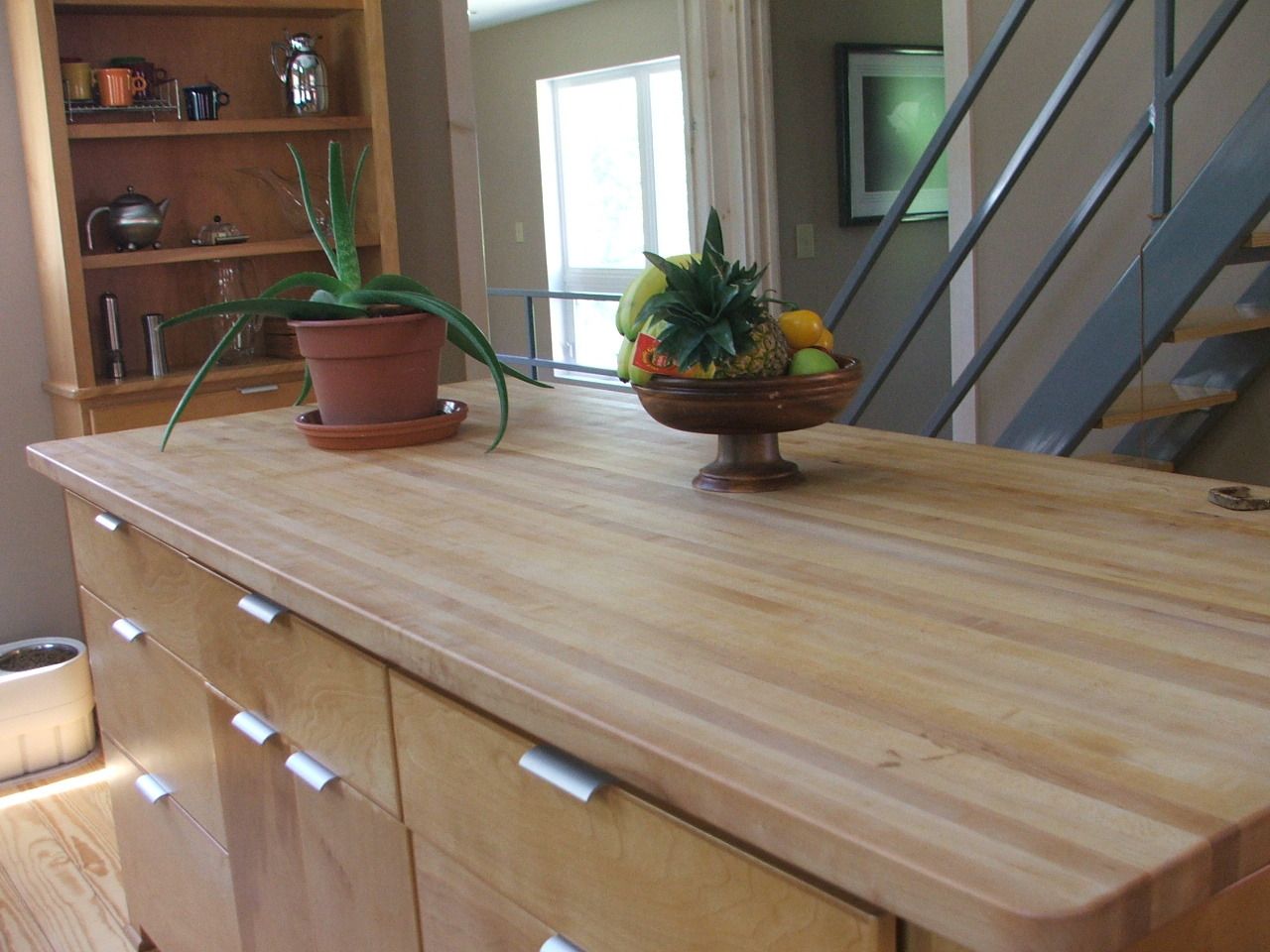 Wooden countertop with potted plants in a bright home interior near stairs