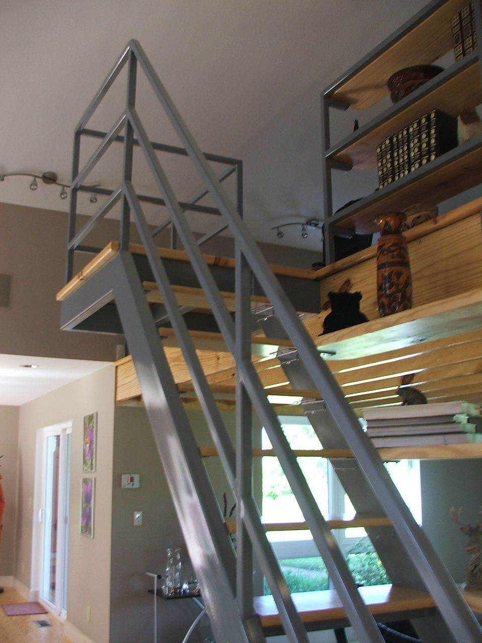 Indoor loft with a metal staircase leading to a mezzanine and shelves on the right