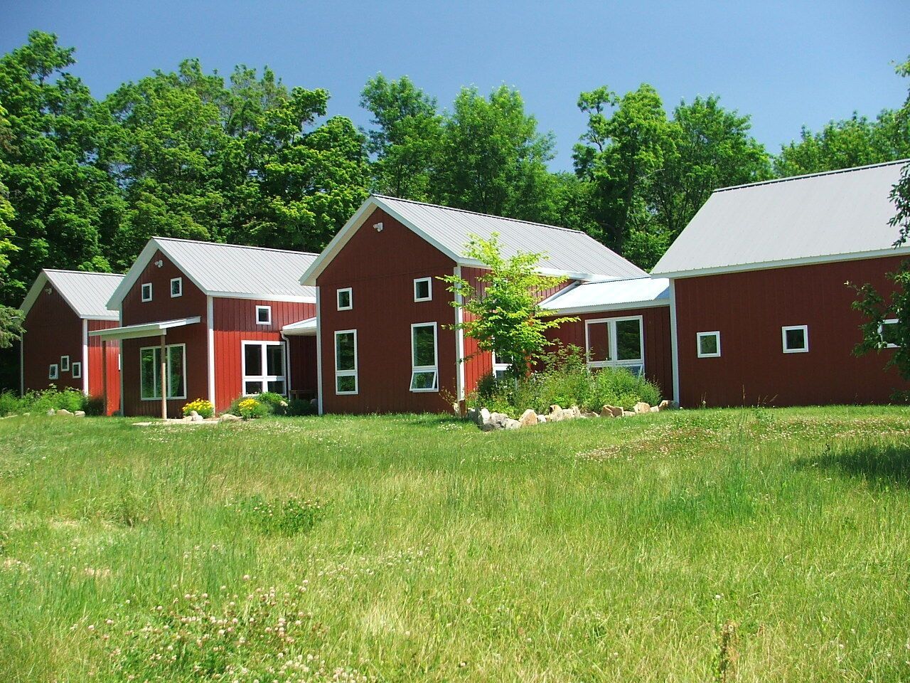 Red buildings with white roofs in a grassy field under a clear blue sky