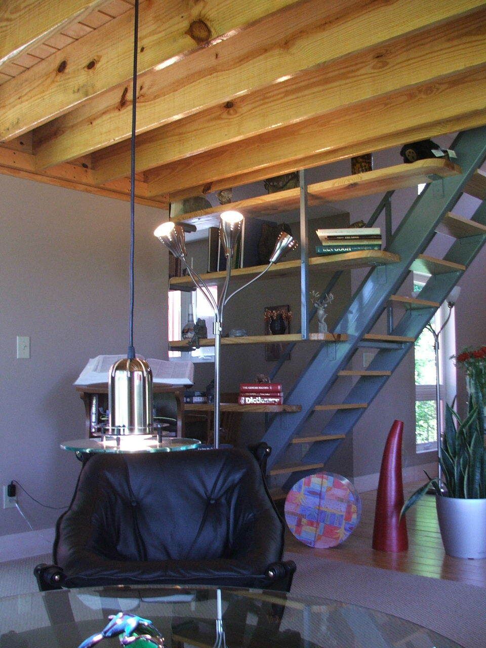 Modern room with exposed beams, staircase, hanging lamp, black chair, and colorful ball.