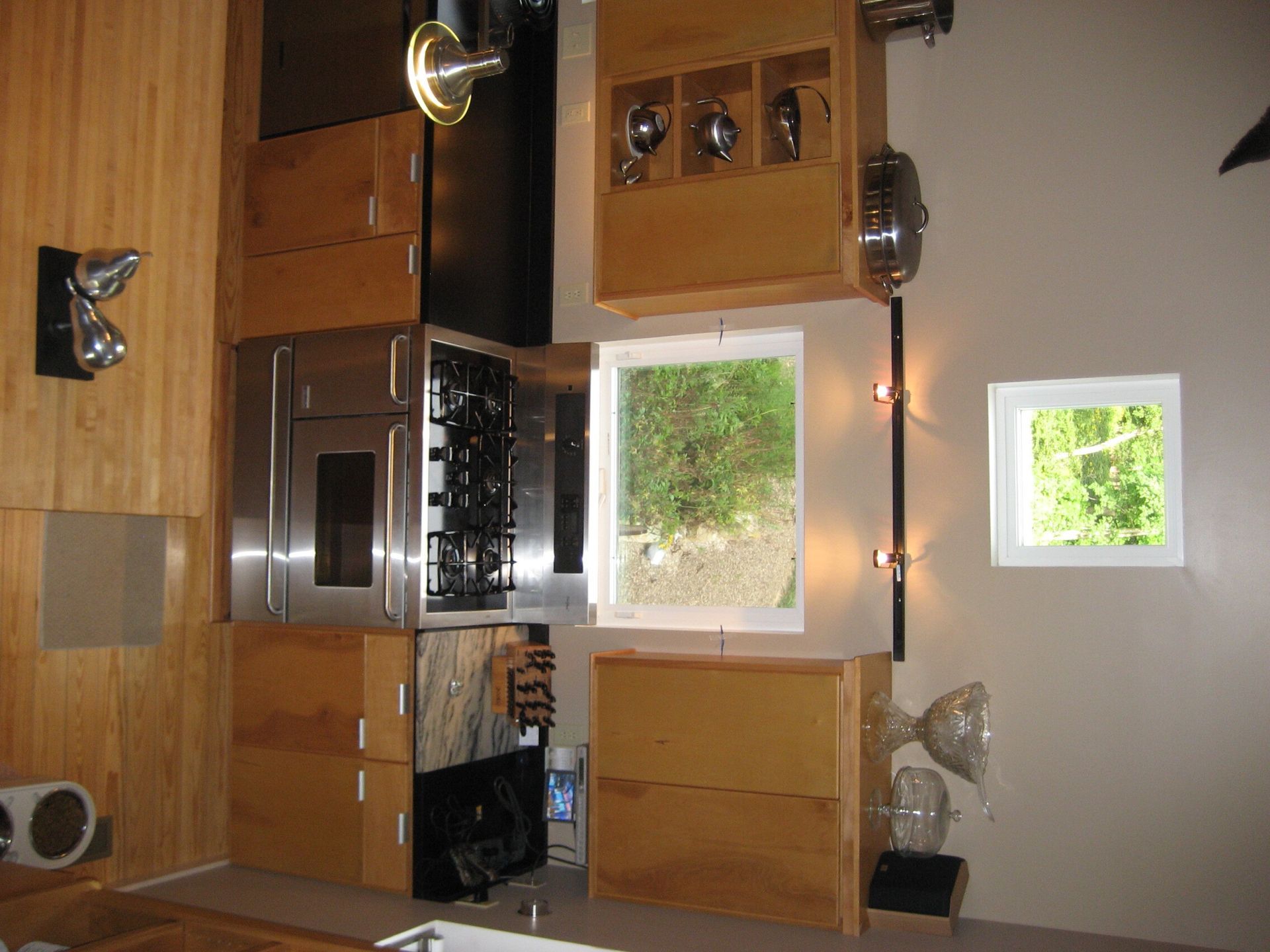 Upside-down kitchen with wooden cabinets, stainless stove, window, and small dining table