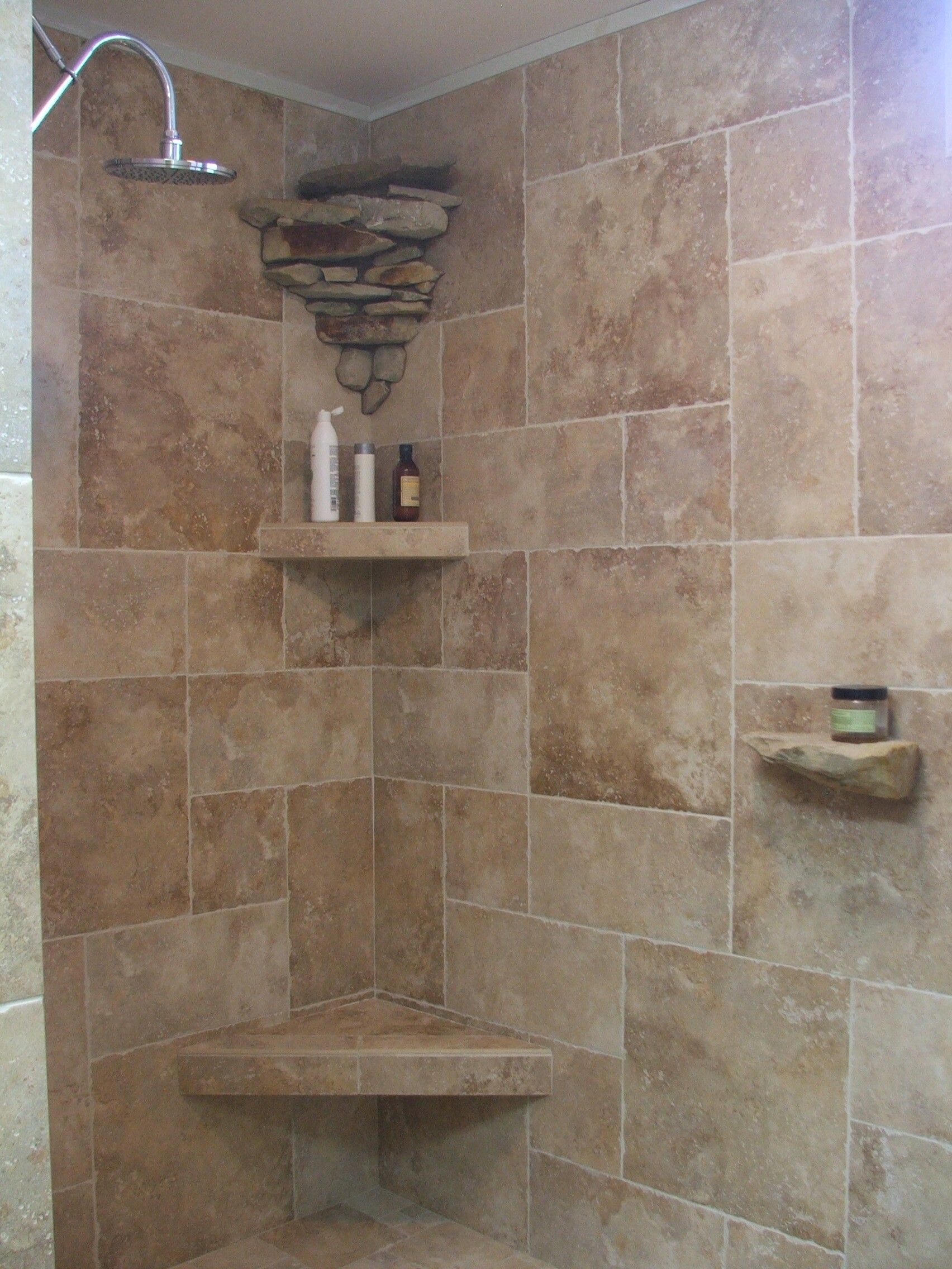 Corner shower with beige tile, corner shelves, and a wall-mounted soap dish