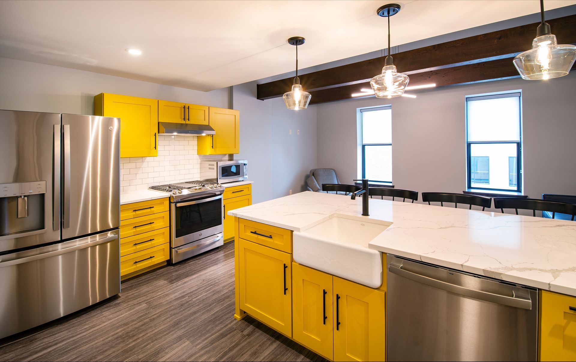 Modern kitchen with stainless steel appliances, yellow cabinets, and a large white island.
