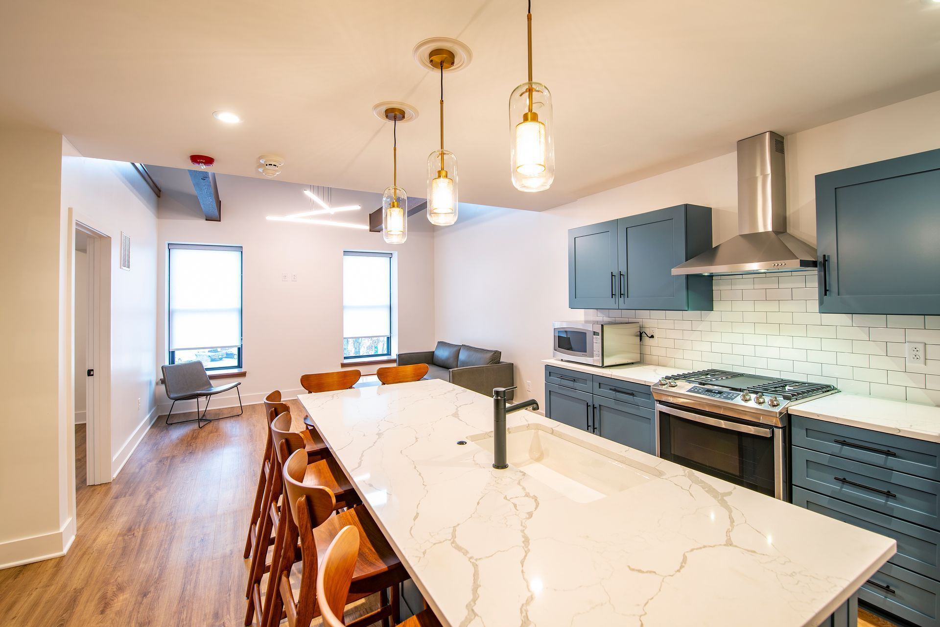 Bright modern kitchen with blue cabinets, white island, pendant lights, and hardwood floors.