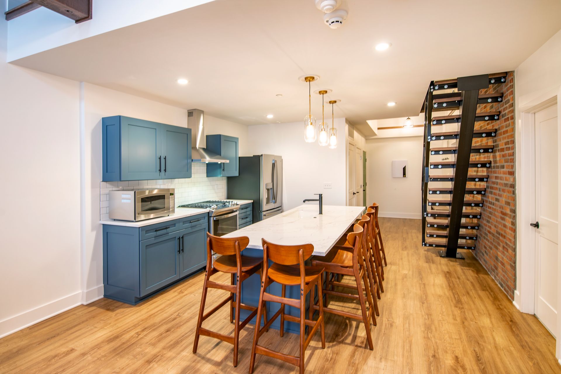 Modern kitchen and dining area with blue cabinets, island seating, and a staircase to the right.
