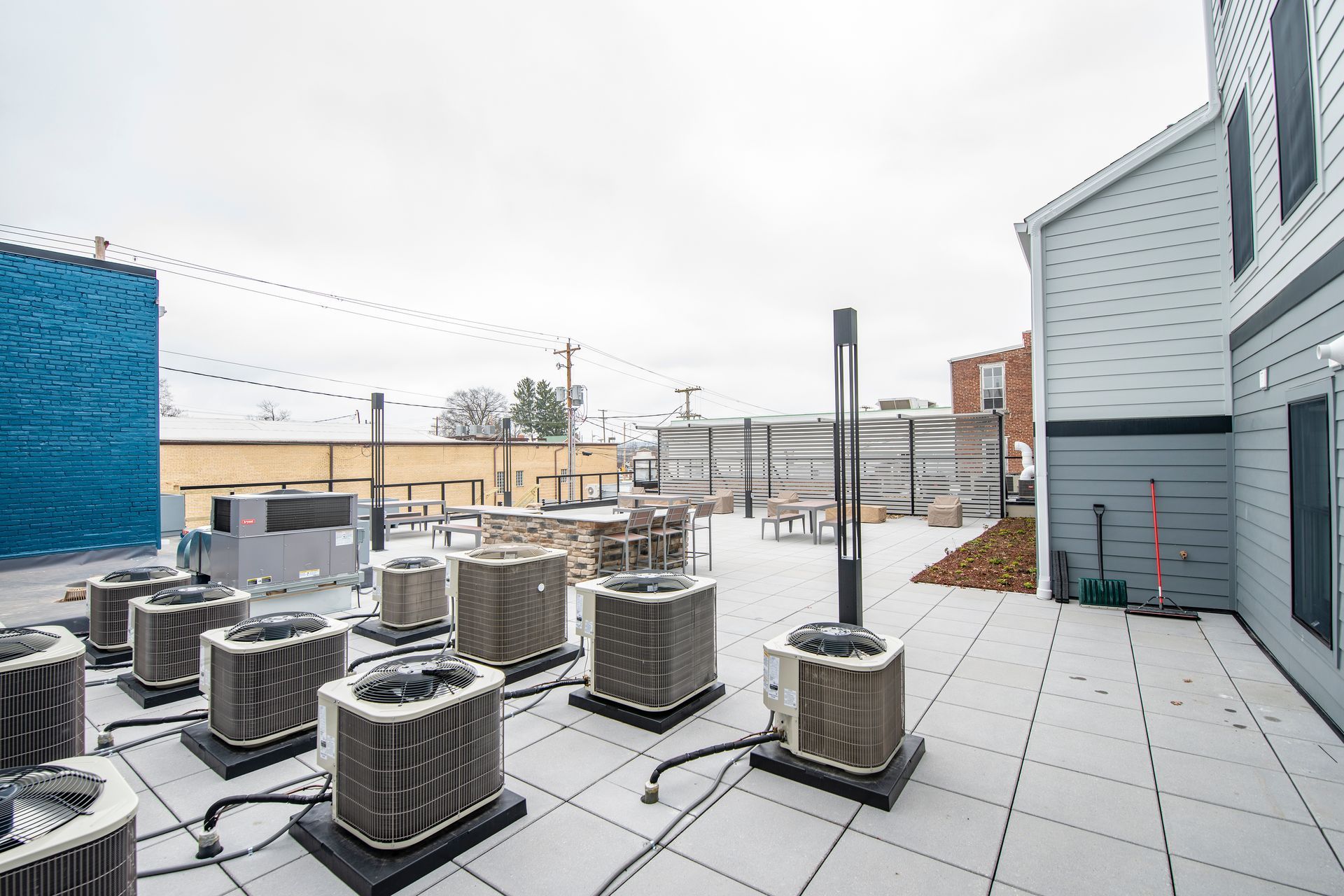 Rooftop HVAC units on a flat roof beside a gray building under an overcast sky.