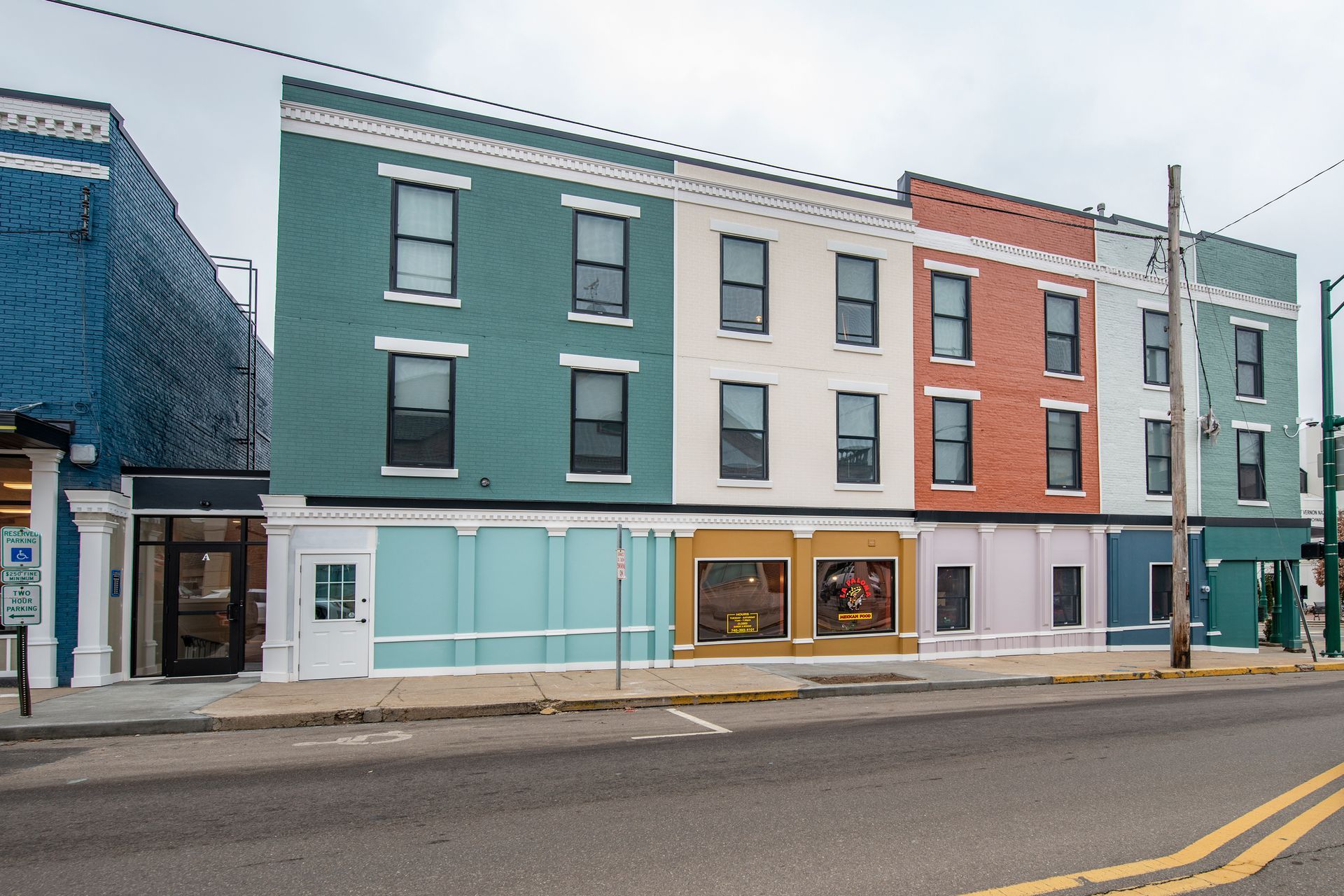 Row of colorful storefront buildings along a street on an overcast day.