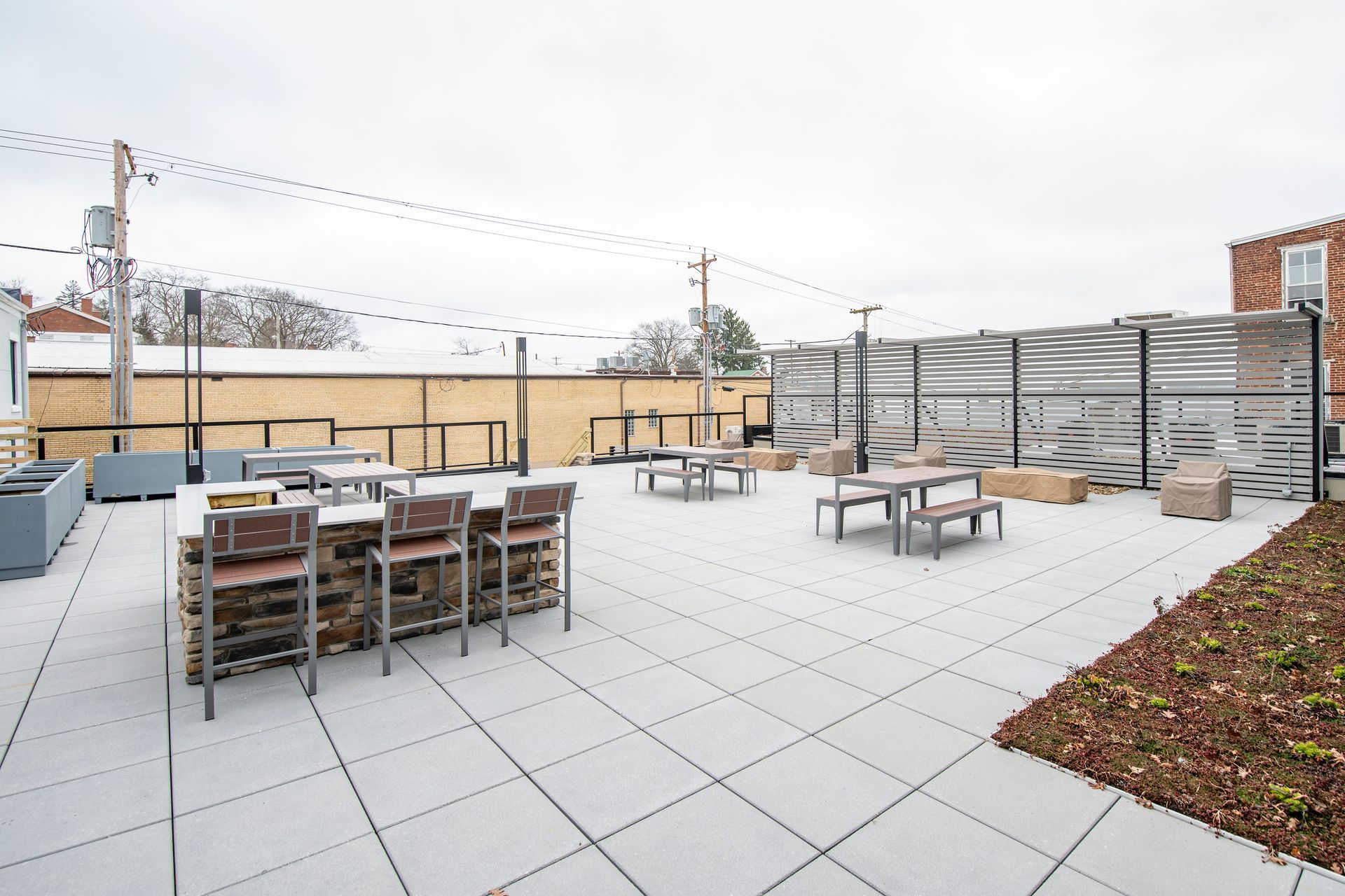 Rooftop patio with tables, chairs, and string lights on a cloudy day.