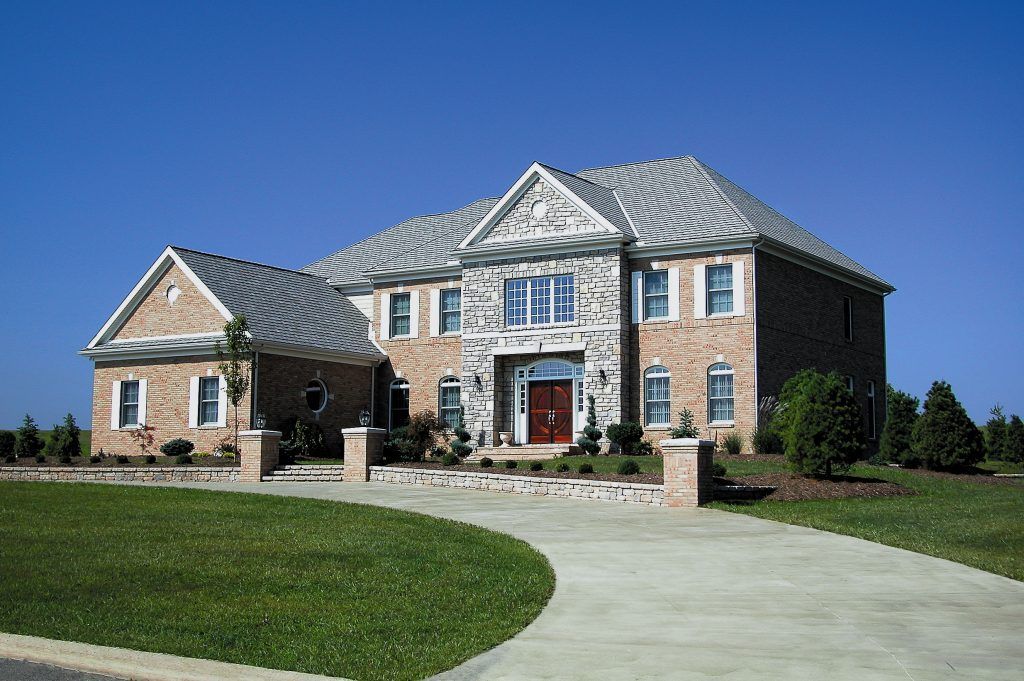 A large brick house with a gray roof and a red door.