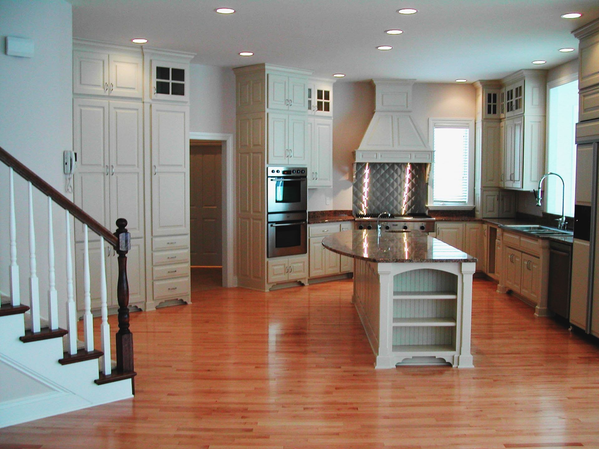 A kitchen with a large island and stairs leading up to it.