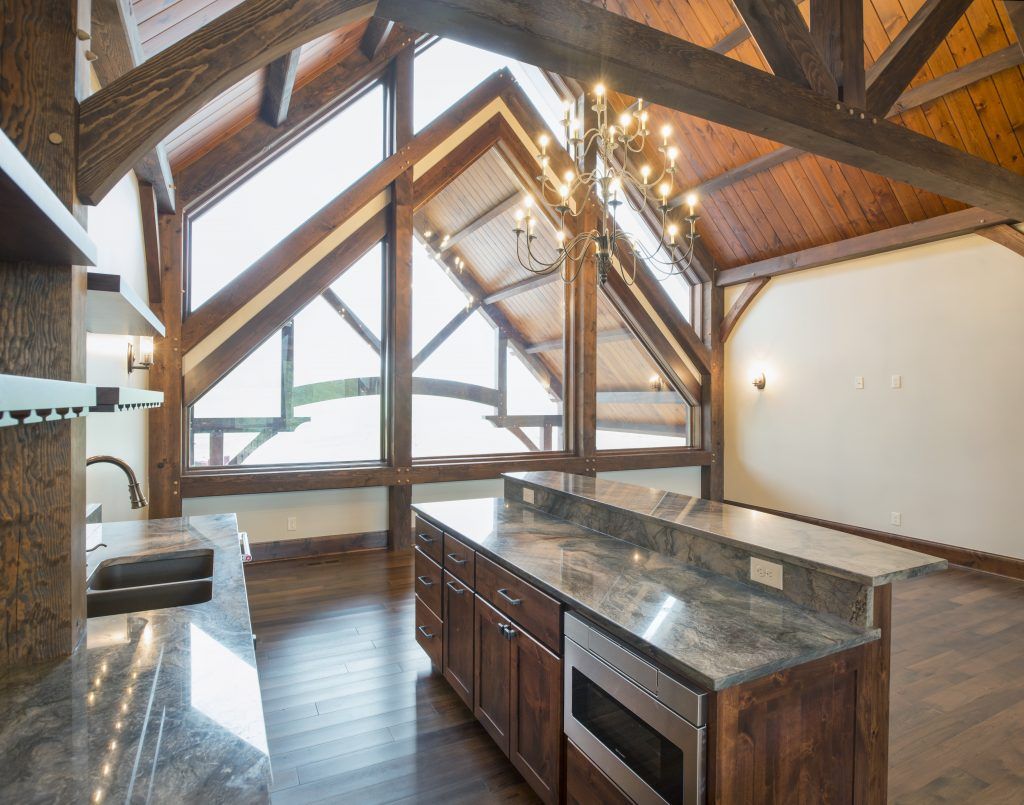 A kitchen with a large island and lots of windows.