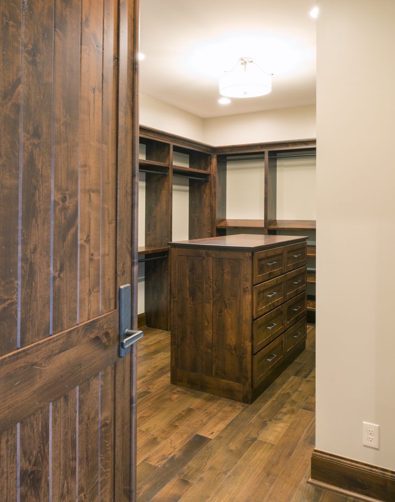 A walk in closet with hardwood floors and a large island in the middle.