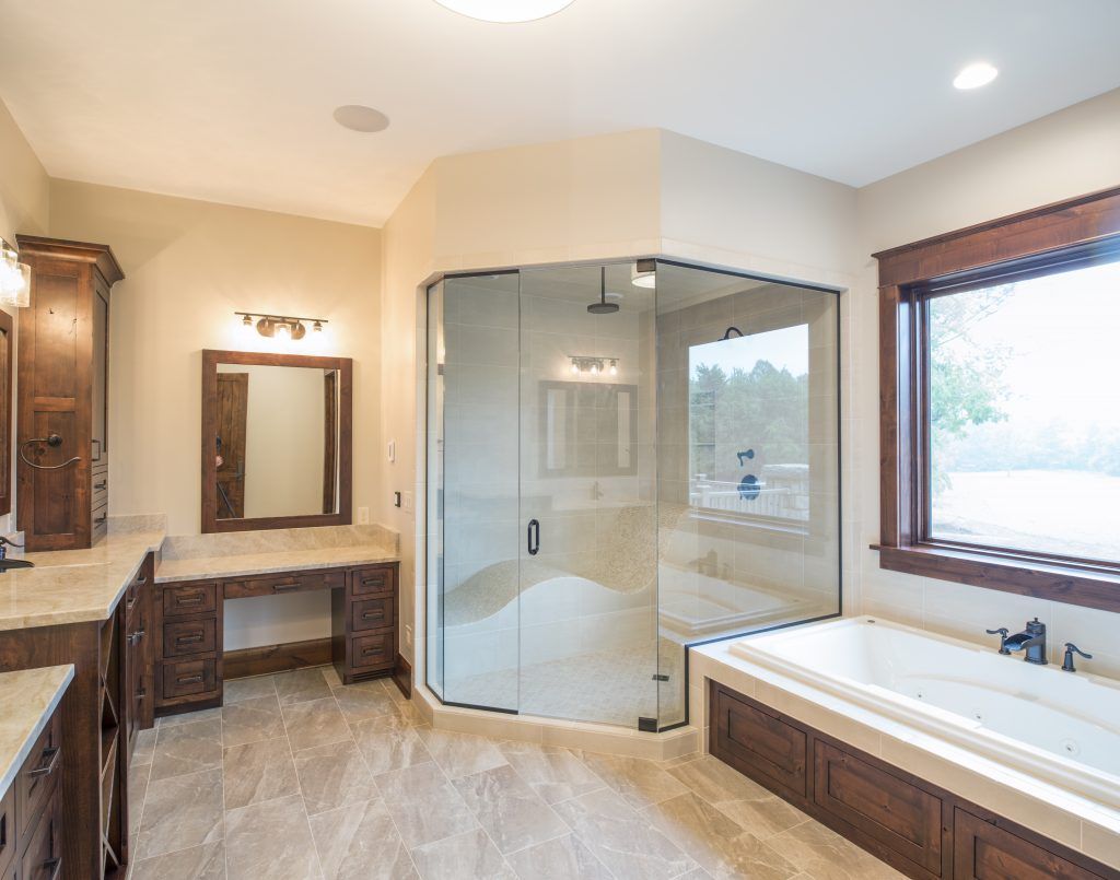 A bathroom with a tub , sink , mirror and shower.