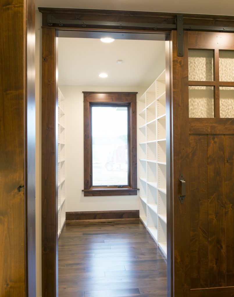 A walk in closet with a sliding barn door and shelves.