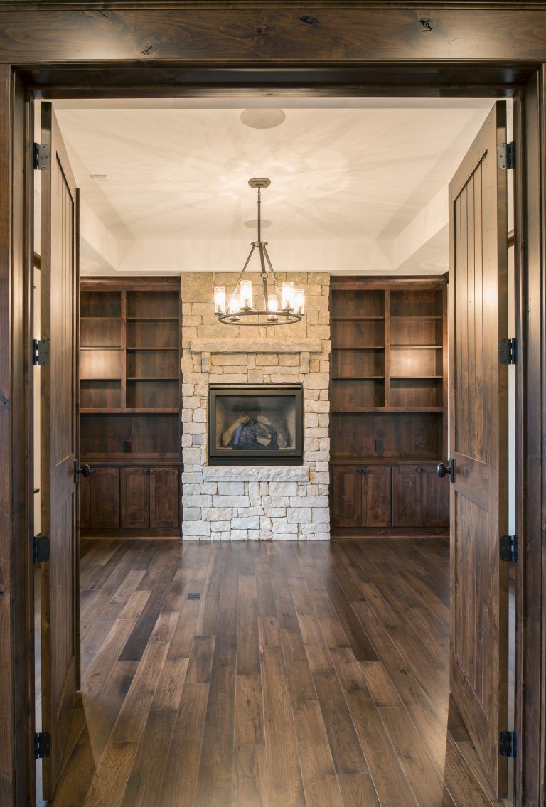 There is a fireplace in the middle of the room with hanging light fixture.
