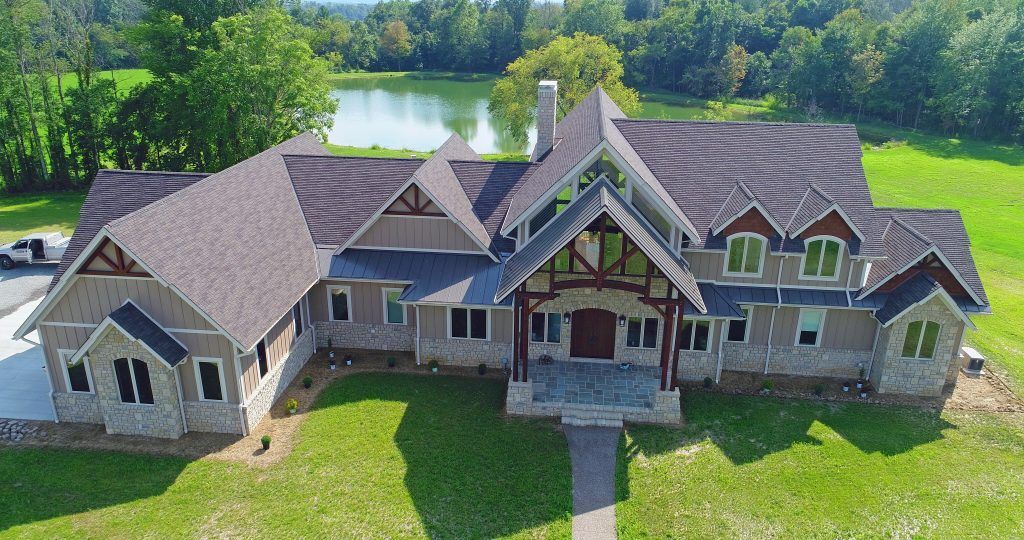 An aerial view of a large house with a lake in the background.