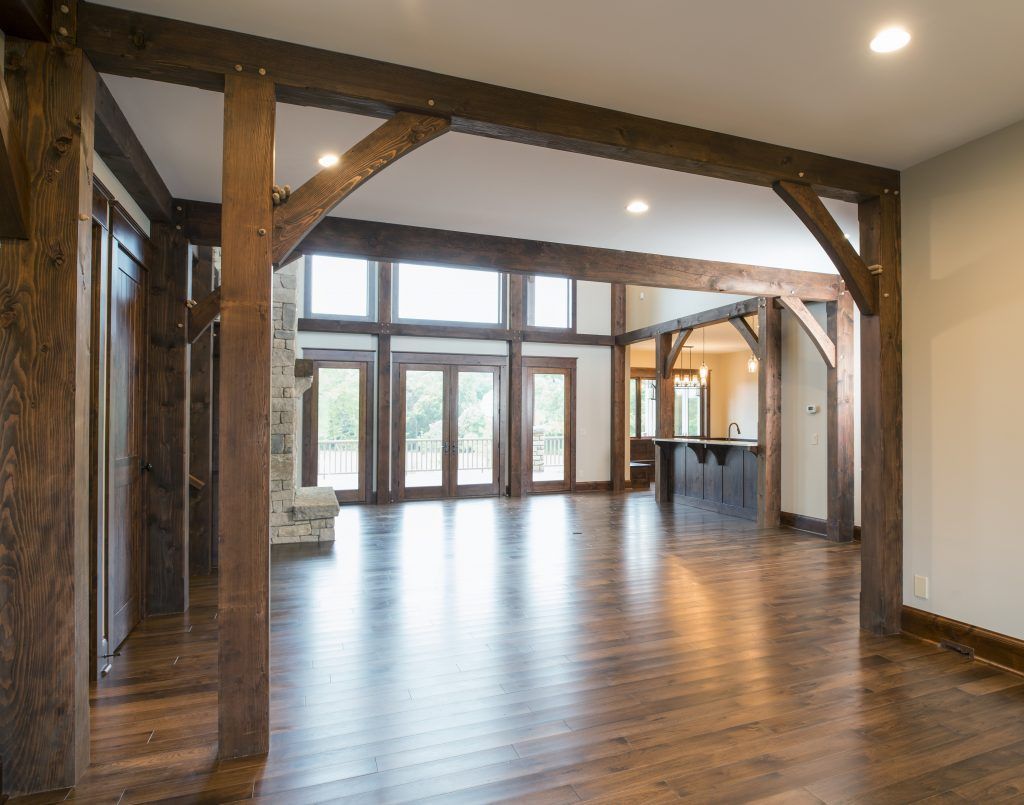 A large empty room with hardwood floors and wooden beams.