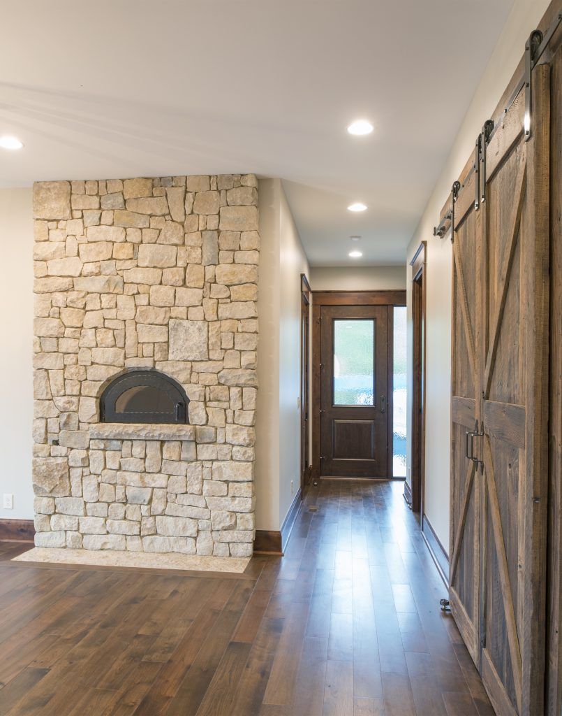 A hallway with a stone fireplace and sliding barn doors.
