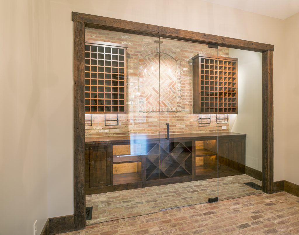 A wine cellar with a brick wall and sliding glass doors.