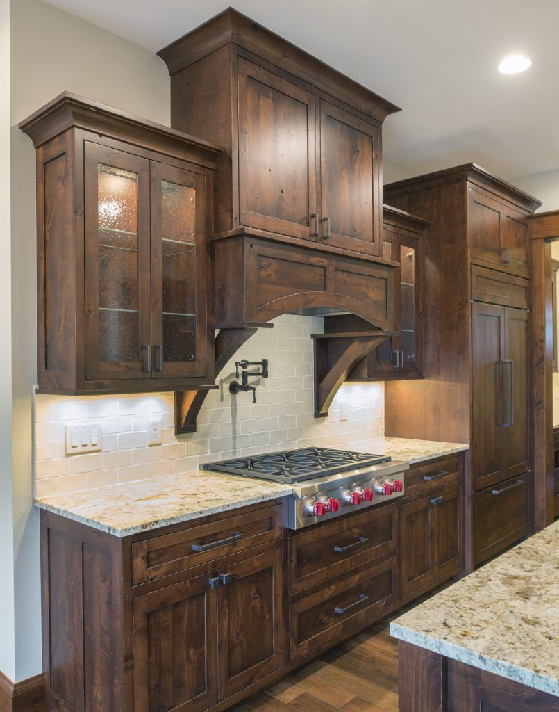 A kitchen with wooden cabinets , granite counter tops and a stove top oven.