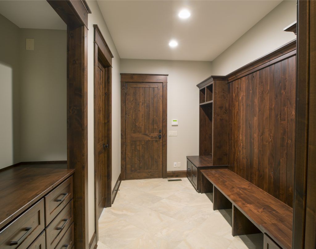 A hallway with wooden cabinets and a bench.