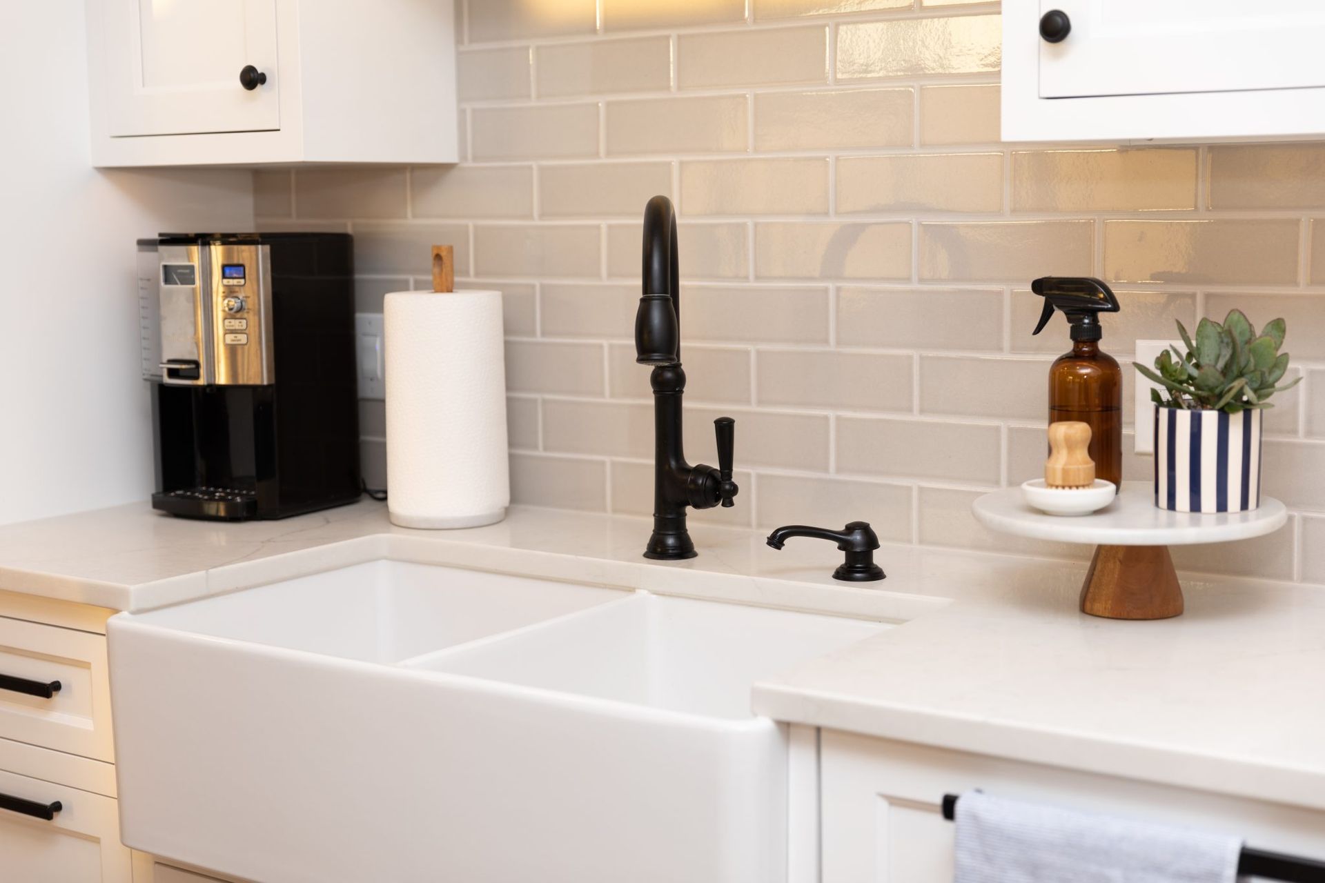 A kitchen with a white sink and a black faucet.