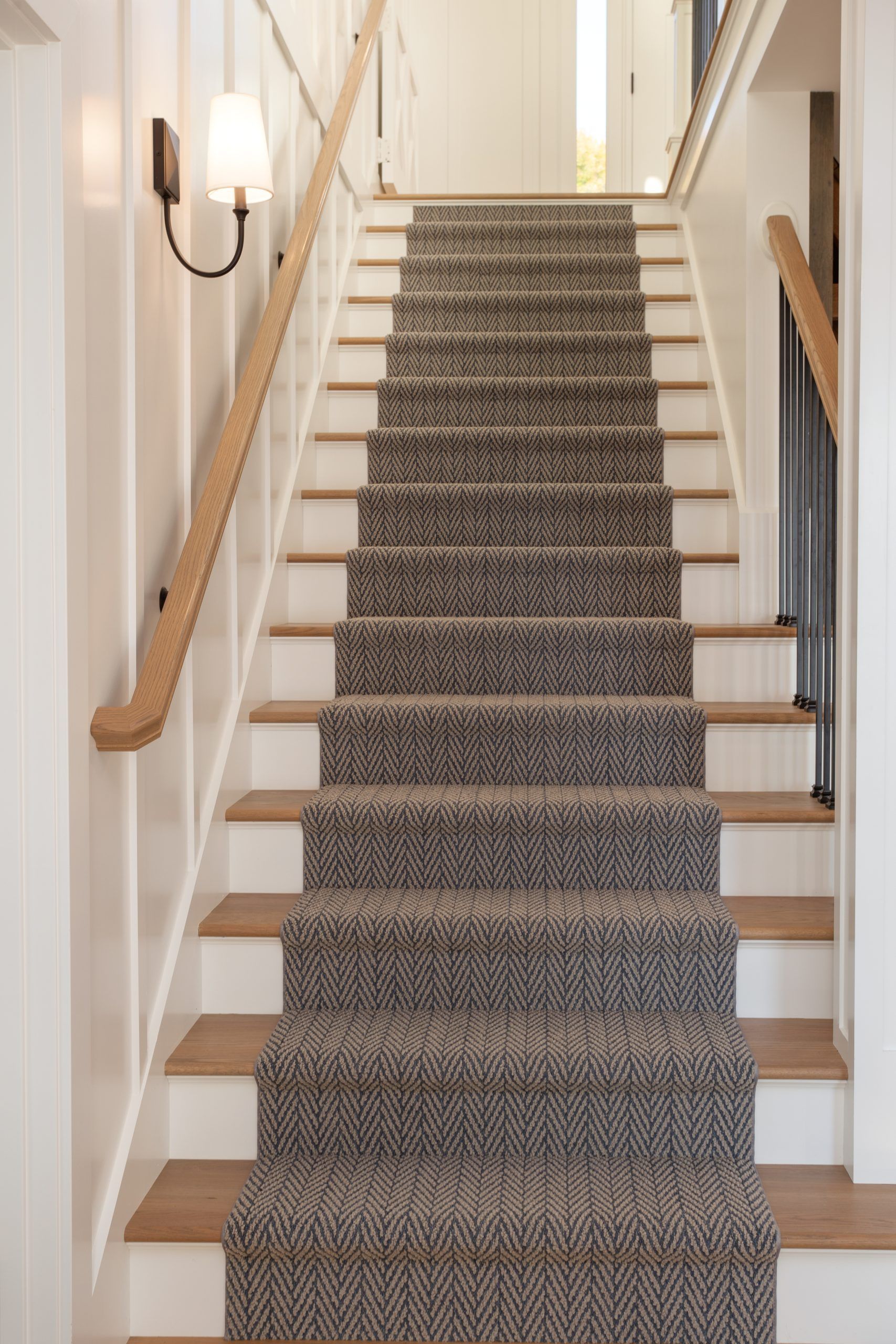 A staircase with a carpet on the steps and a wooden railing.