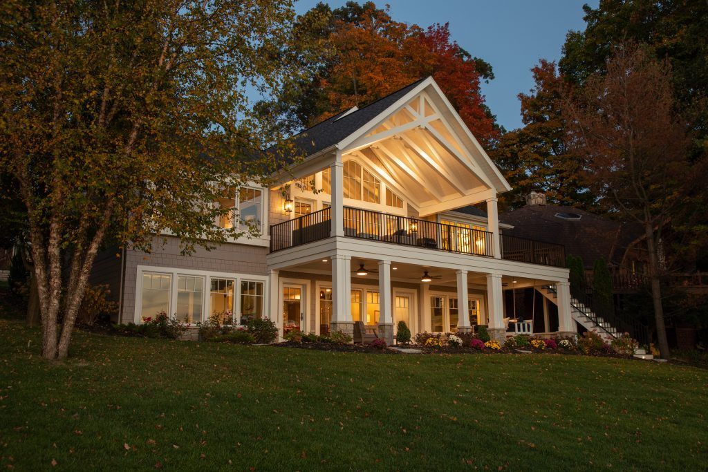 A large white house with a large porch is lit up at night.