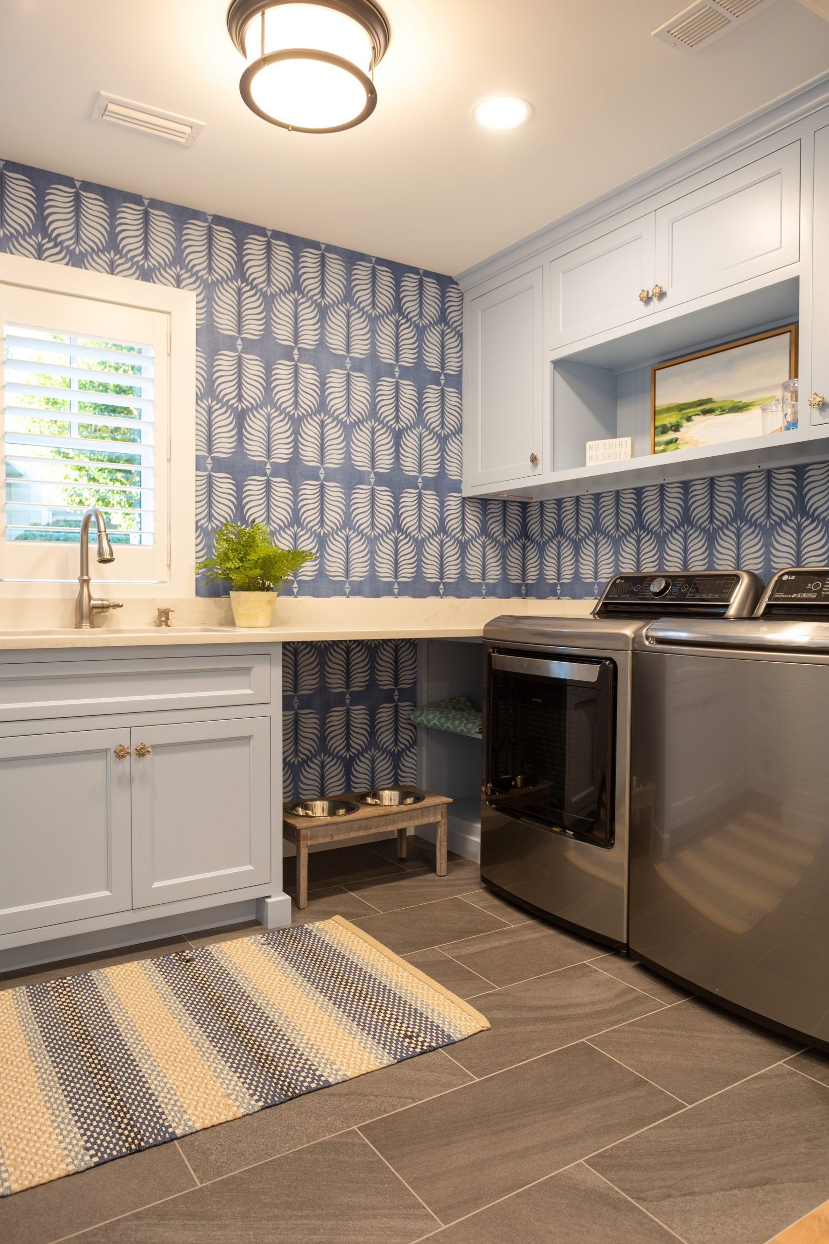 A laundry room with a washer and dryer, sink, and rug.