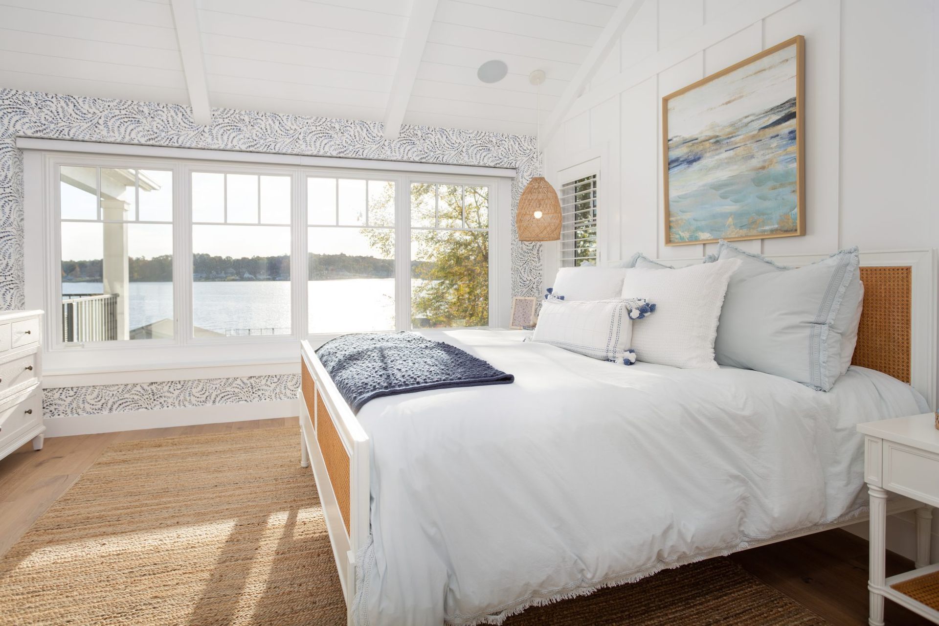 A bedroom with a large bed and a large window overlooking the water.