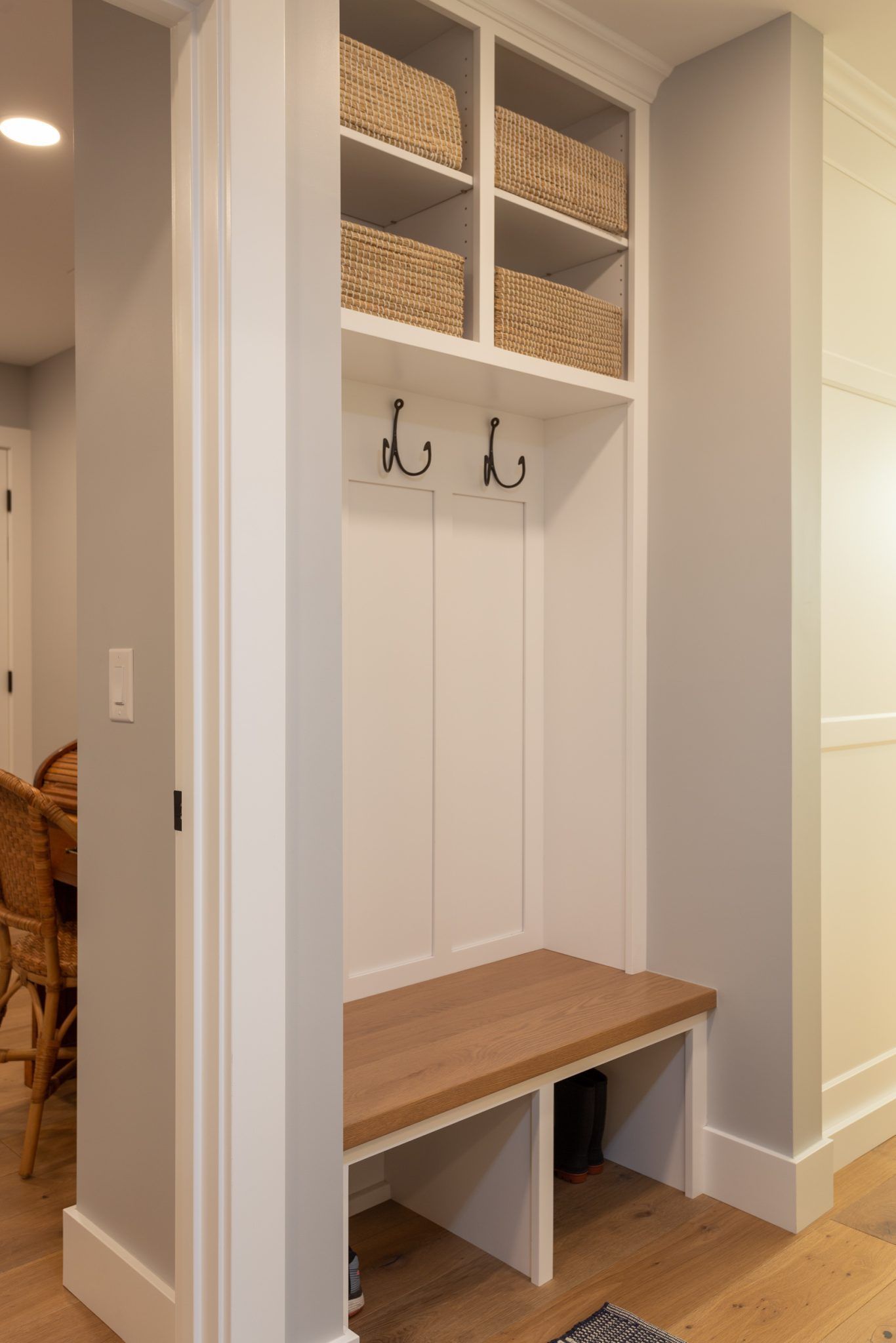 A hallway with a bench and hooks on the wall.