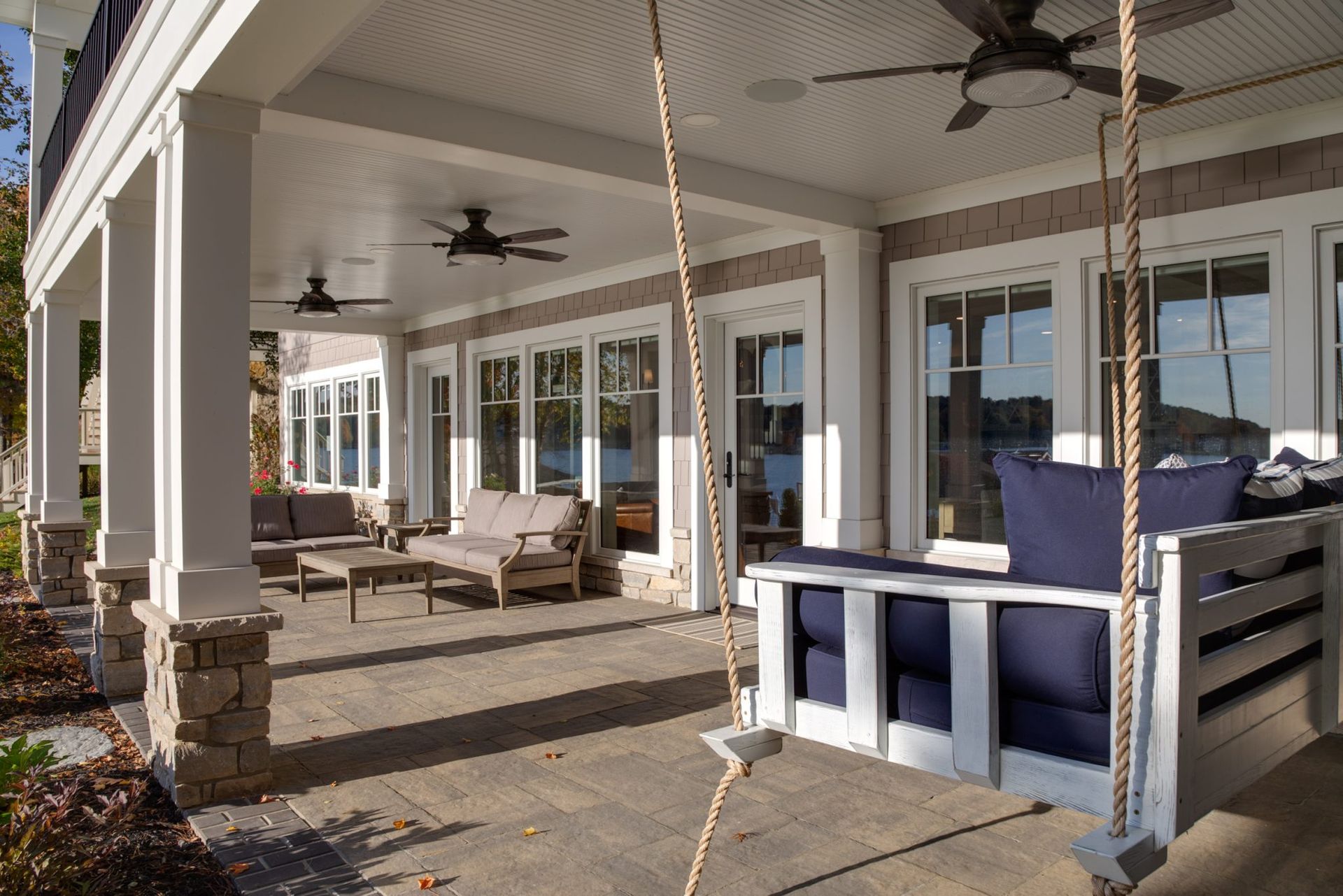 A porch with a swing and a ceiling fan.