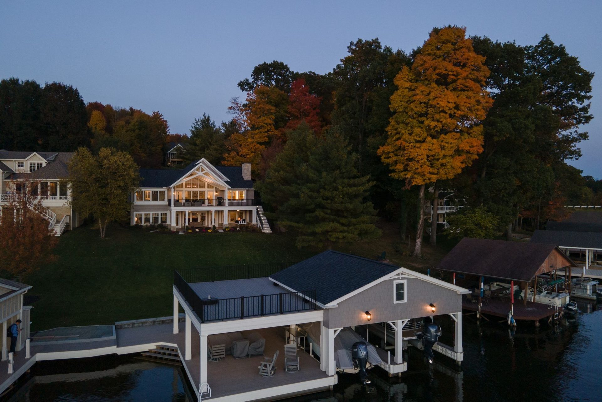 A large house sits on a hill overlooking a body of water.