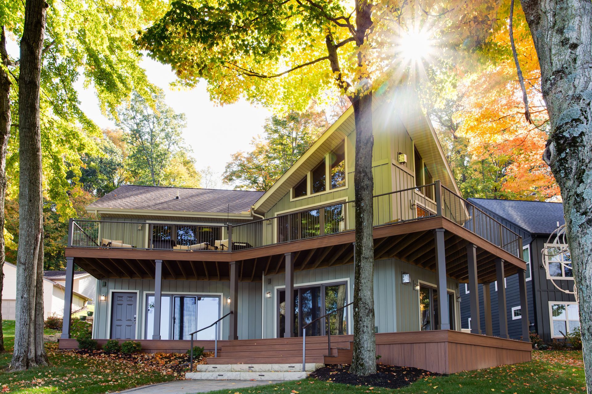 A large house with a large deck is surrounded by trees.